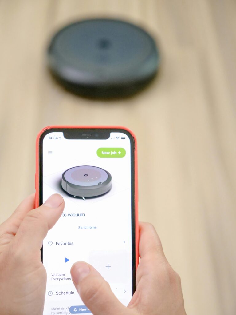 Saugroboter mit Wischfunktion wird per Smartphone-App auf einem Holzboden gesteuert